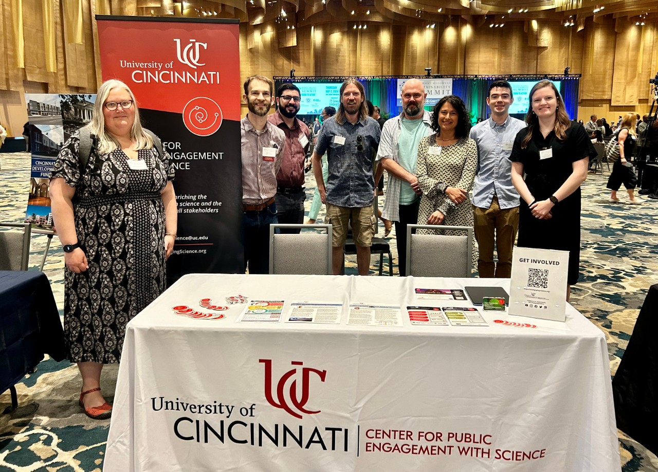 PEWS faculty affiliates stand around a poster at a conference.