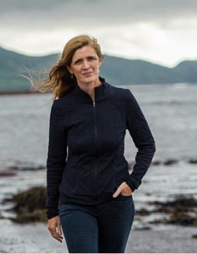 picture of a women with blonde hair and the ocean is behind her