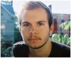 Photo of William wearing black shirt with houses in background