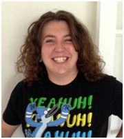 Brittany wearing black shirt that says "Yeahuh" on it in front of white wall