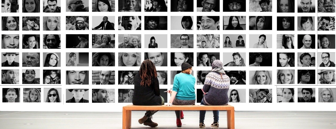 People sitting on bench looking at black and white images of people in a gallery