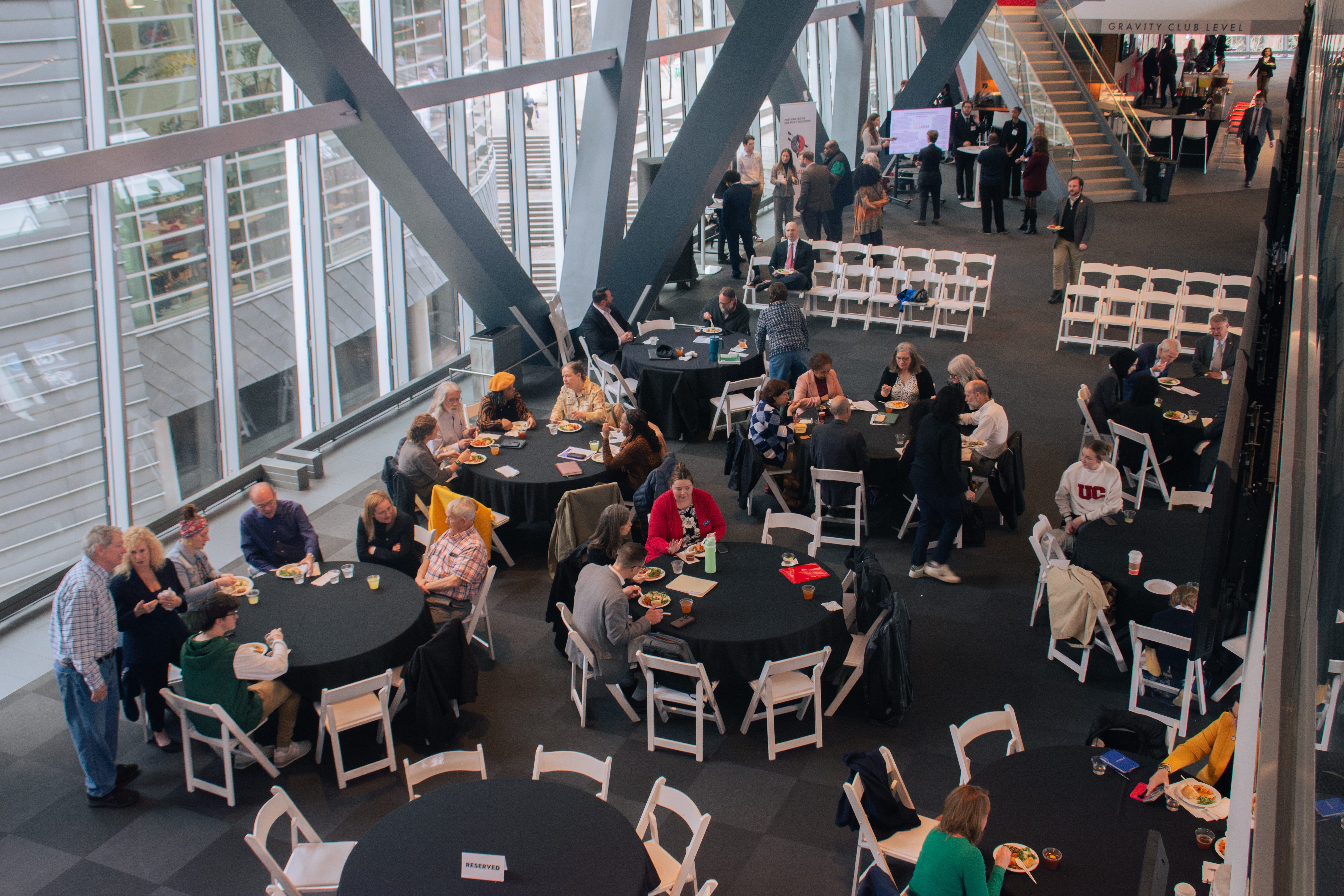 A modern conference room with people networking around presentation boards. Attendees are engaged in discussions, creating a professional and dynamic atmosphere.