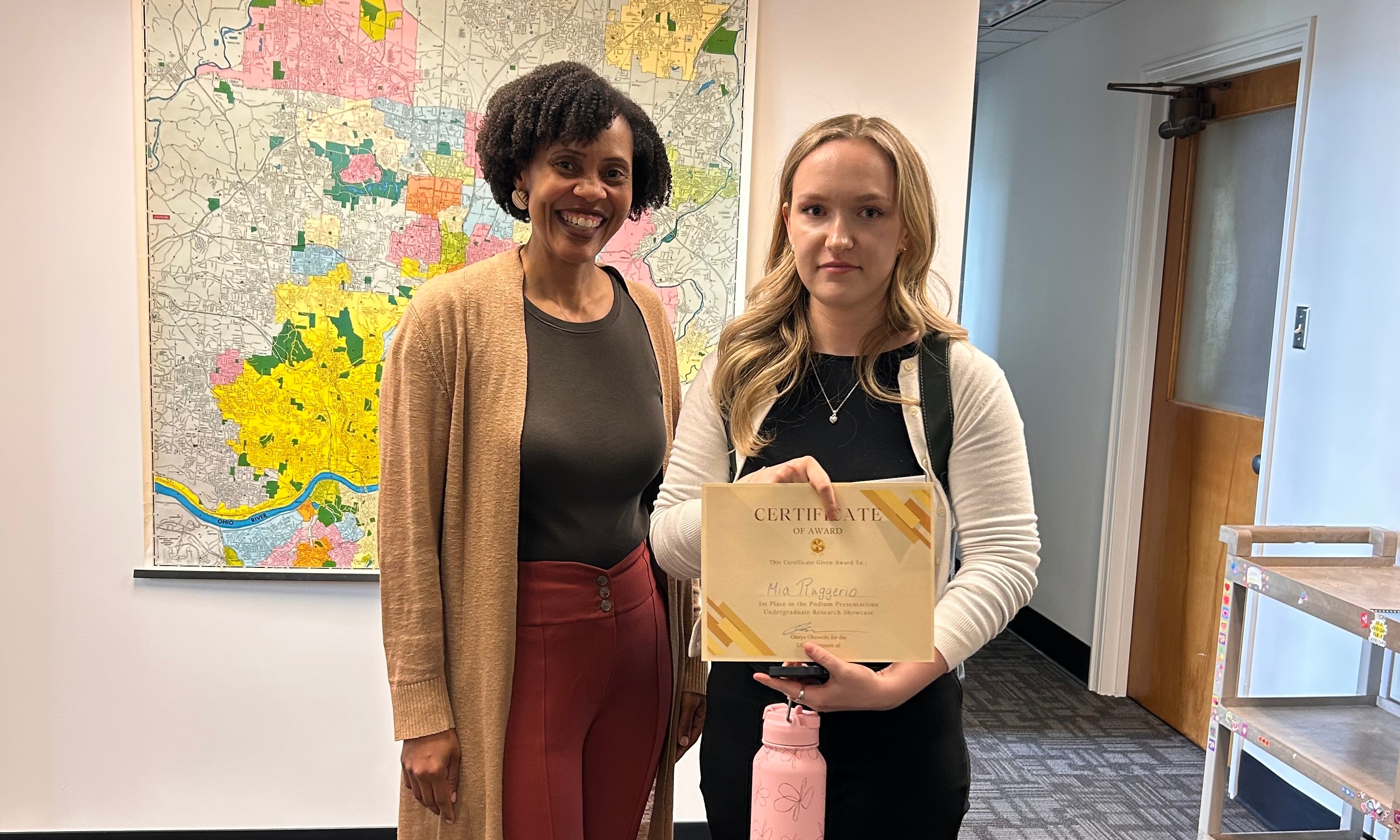 Dr. Okuwobi stands next to the top podium presenter.